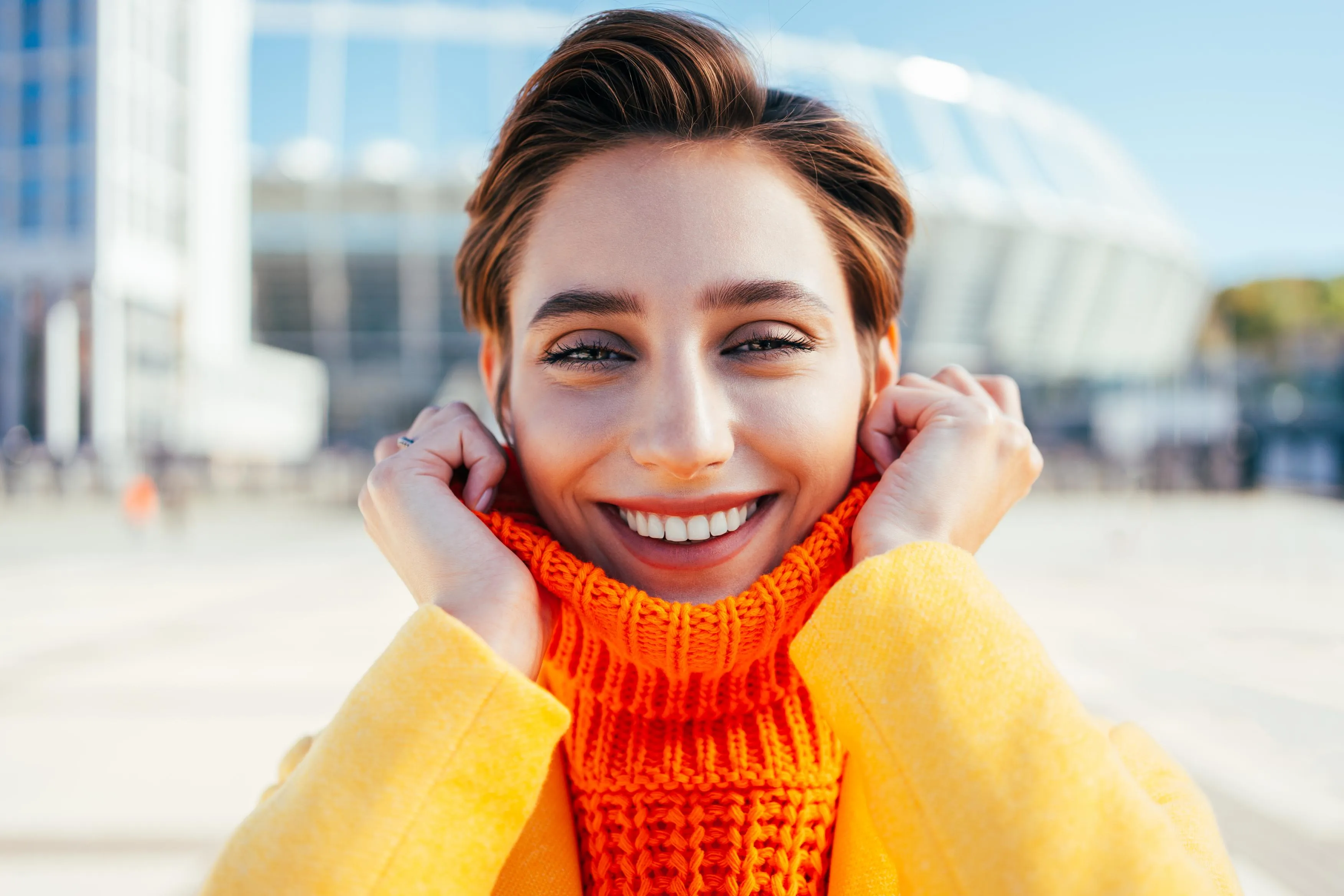 Happy woman smiling confidently outdoors in bright sunlight showing healthy, white teeth representing the results of professional dental care and cosmetic treatment