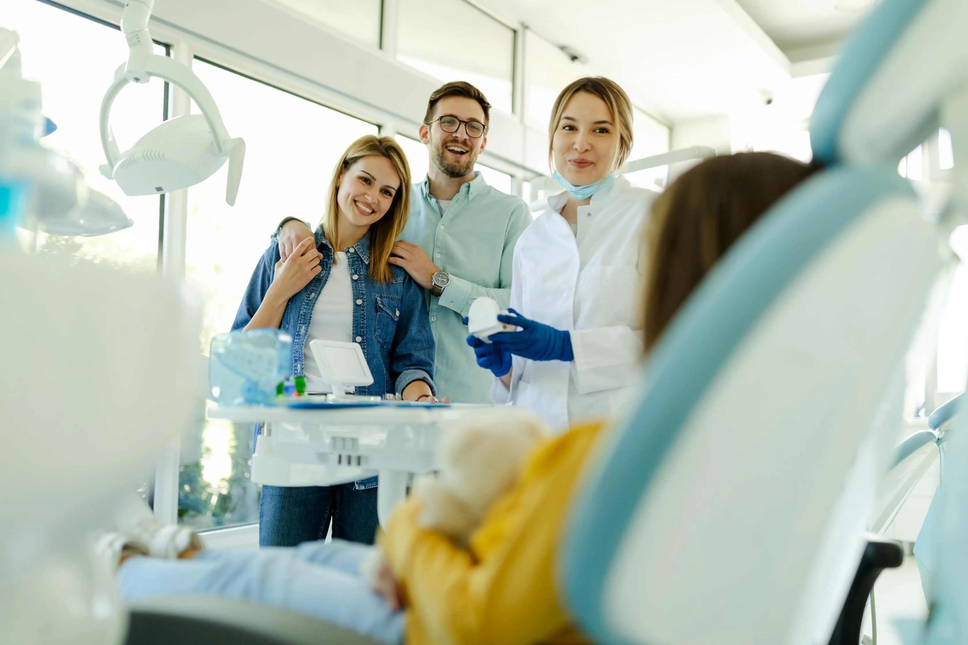 Dentist providing a consultation for a young girl while her parents watch in a bright, welcoming family dental clinic emphasizing compassionate pediatric care