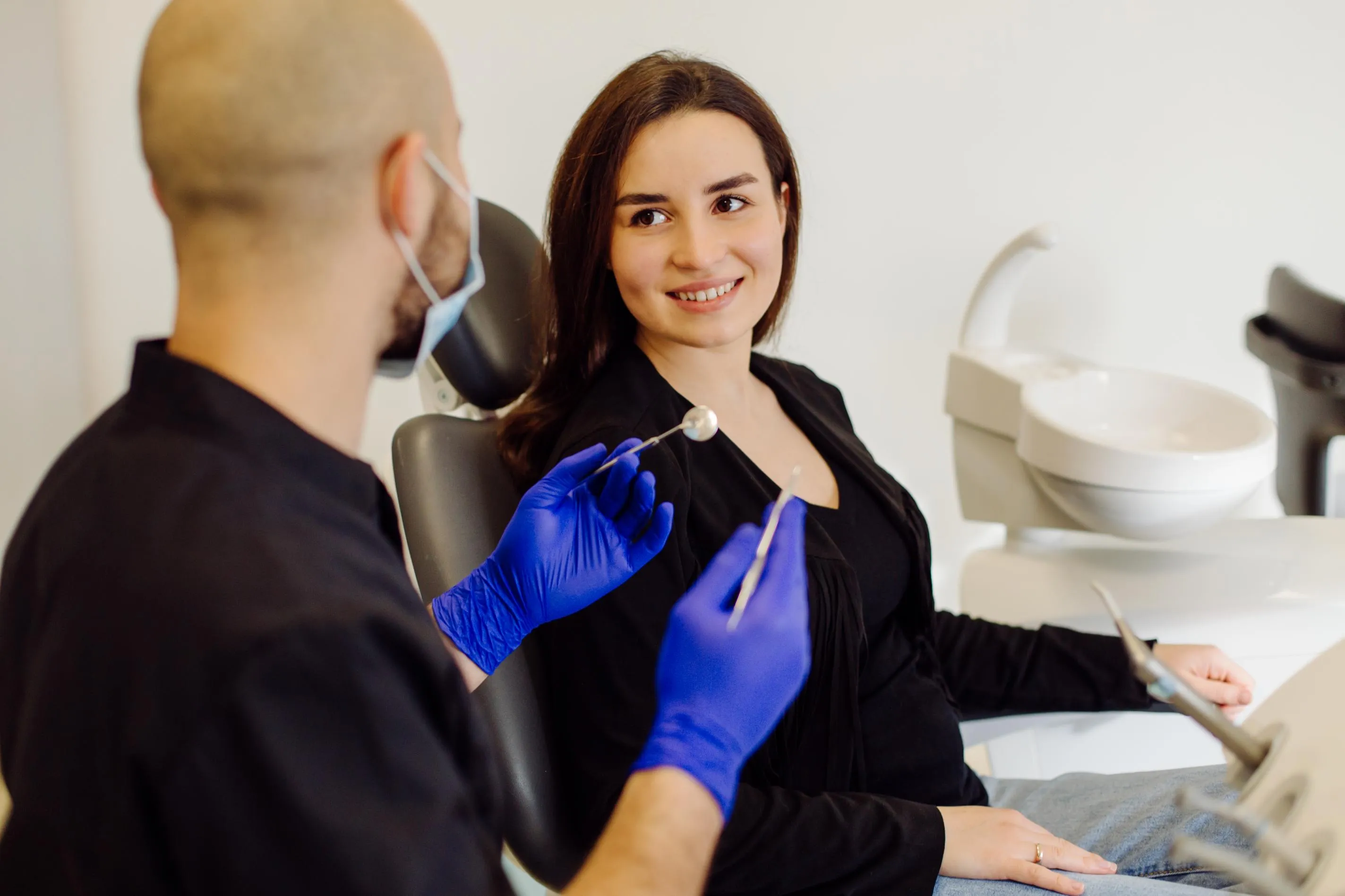 Female patient sitting in a dental chair talking with her dentist about orthodontic treatment options and customized smile correction plans