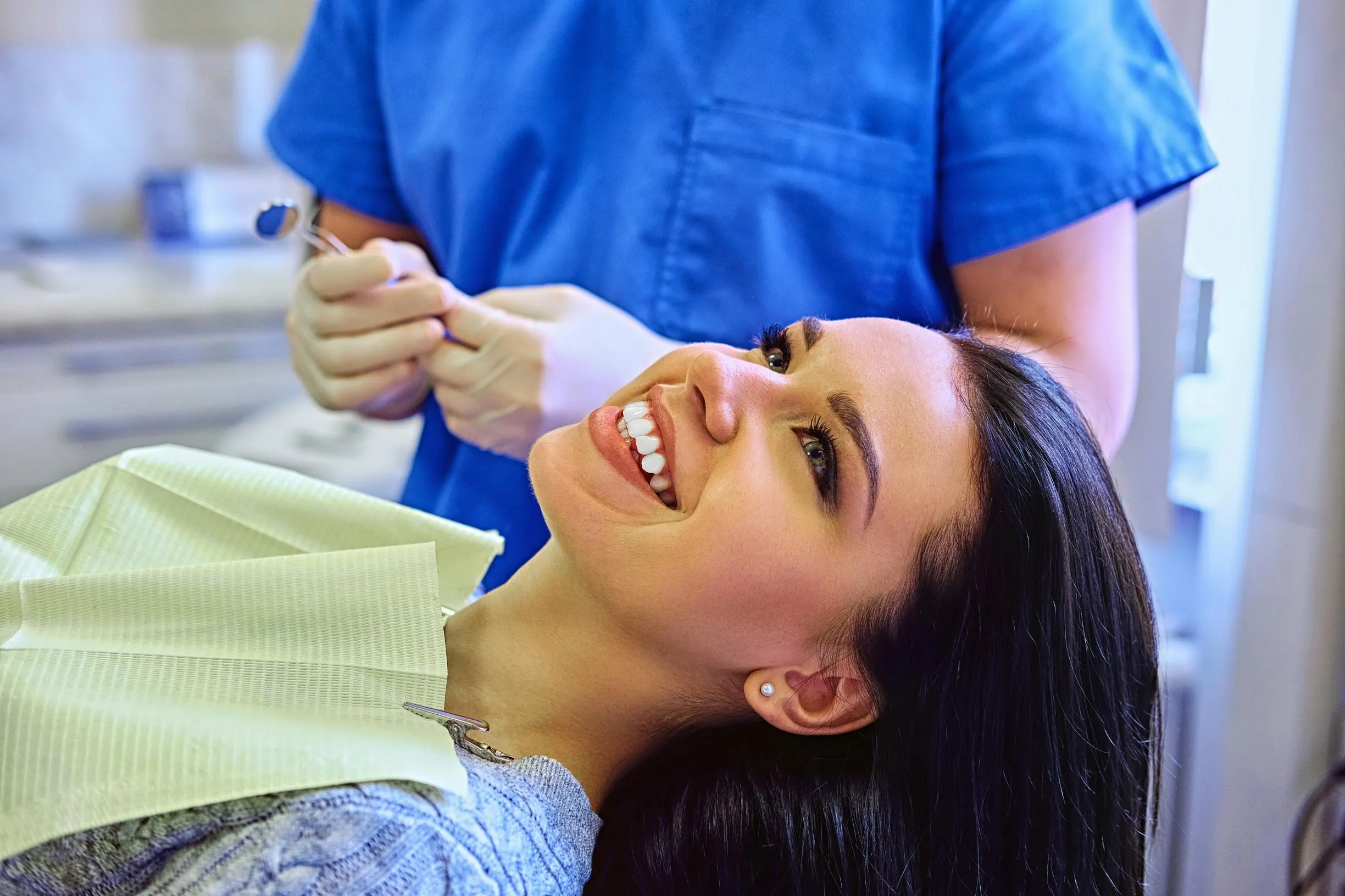Female patient smiling in the dental chair while dentist explains Invisalign treatment plan highlighting comfort and convenience of clear aligners