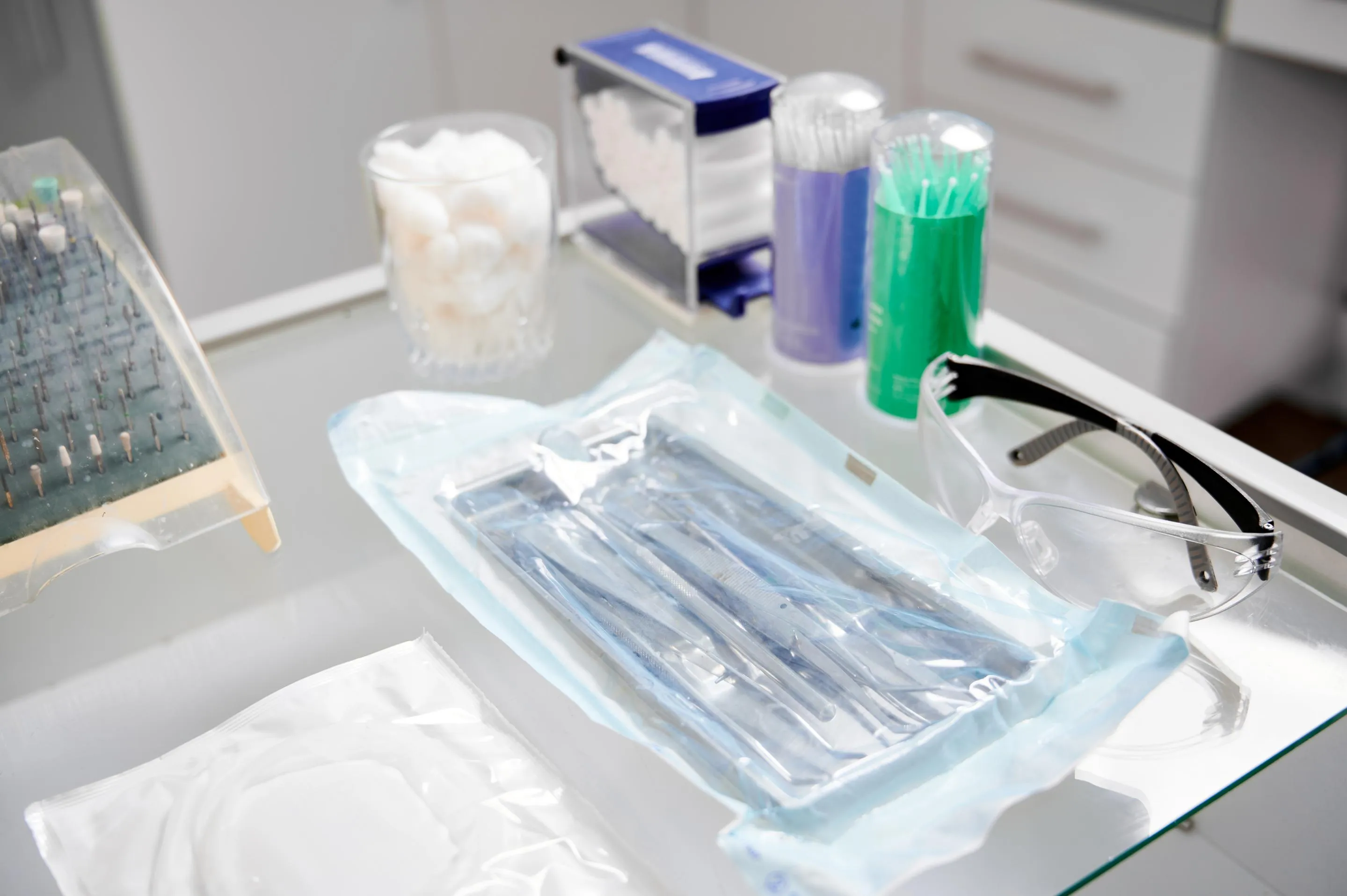 Close-up of dental tools and disposable items placed on a sterilization tray in a clinical setting emphasizing infection control and patient safety standards