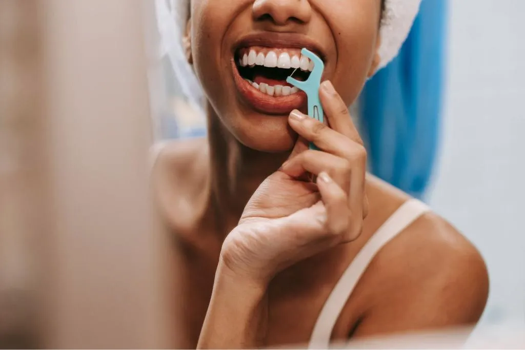 Close-up of a person cleaning between teeth with a small interdental brush demonstrating proper technique for plaque removal and gum health maintenance