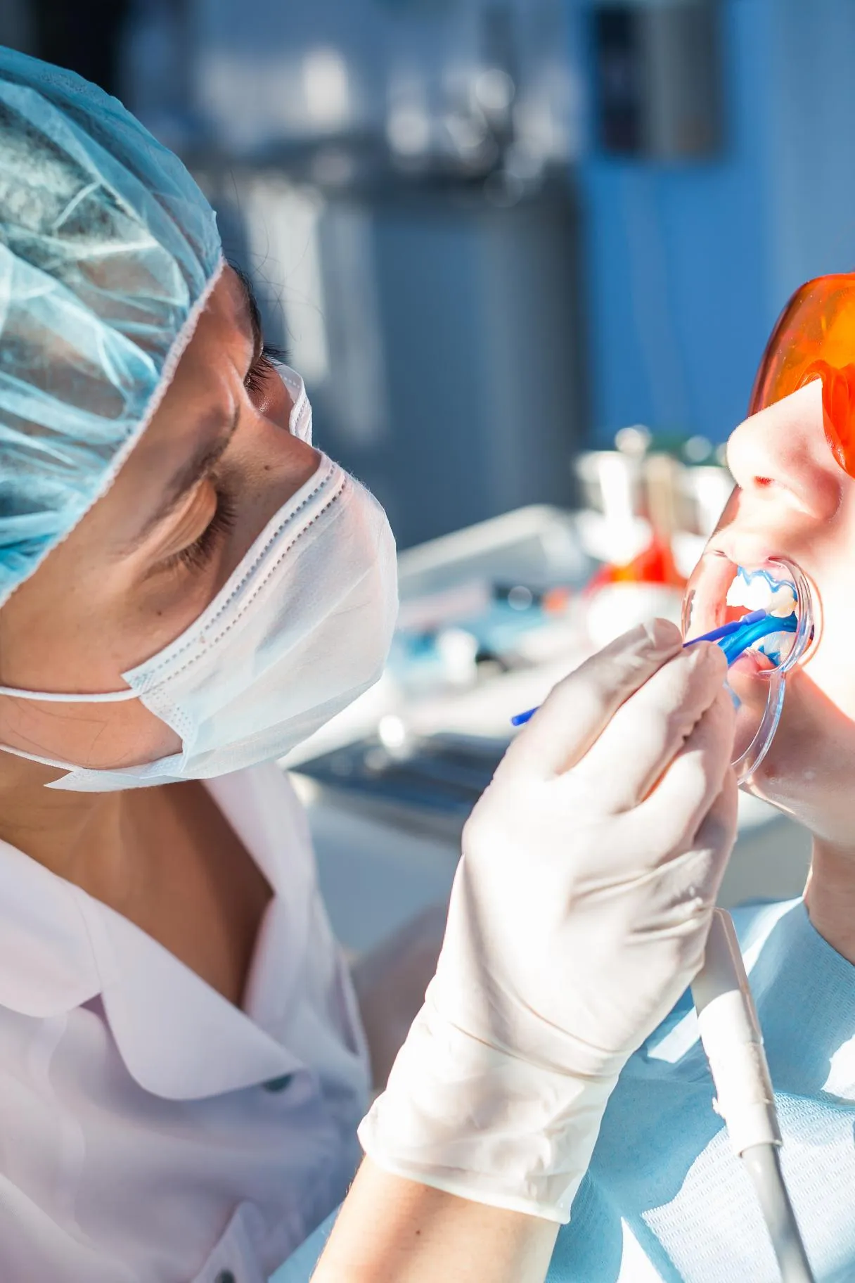 Dentist wearing protective eyewear and gloves polishing a patient’s teeth using professional dental equipment to enhance smile brightness and oral health