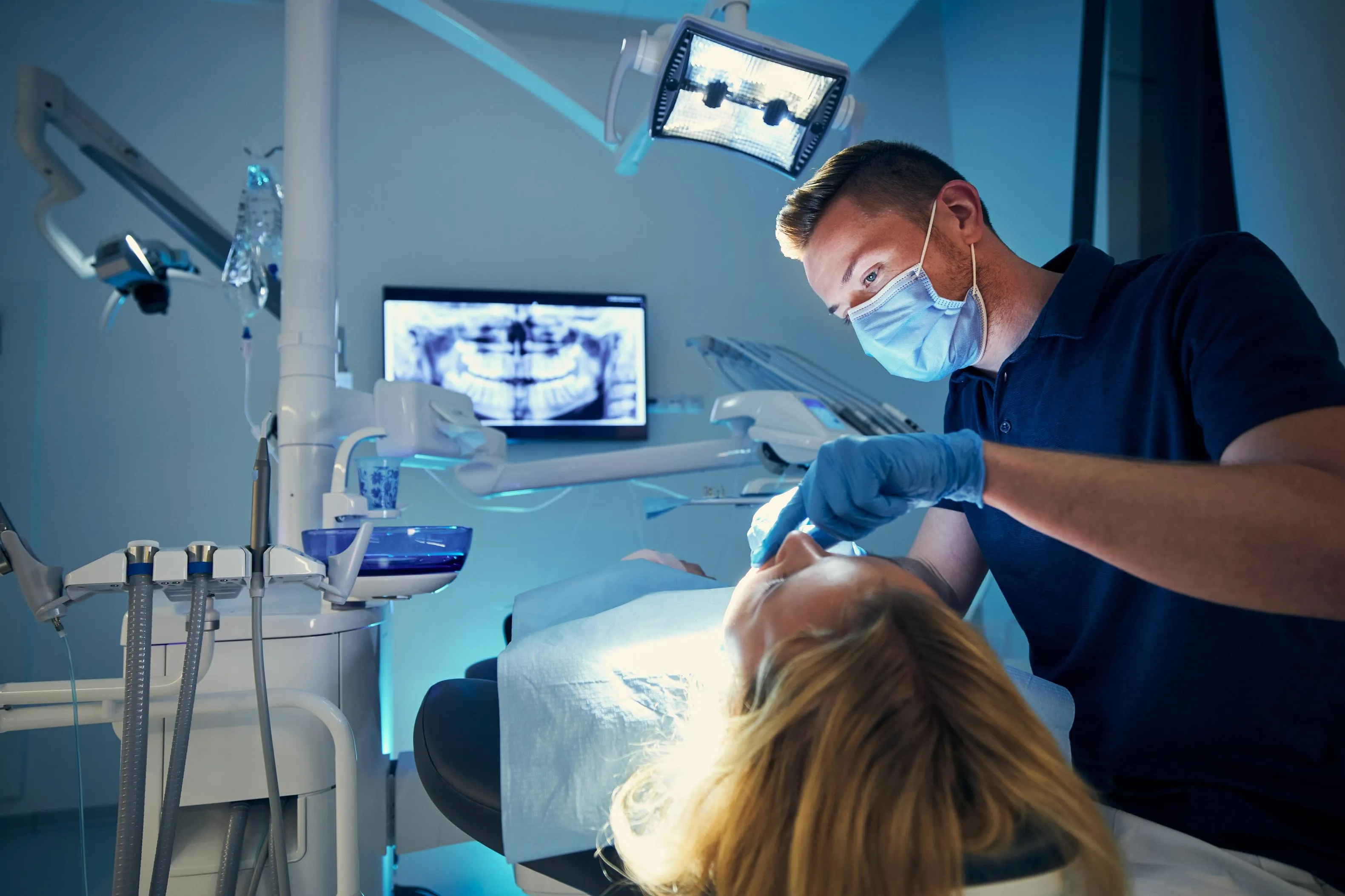 Male dentist using advanced dental imaging equipment during treatment while viewing real-time X-ray scans on a monitor for precision and accuracy