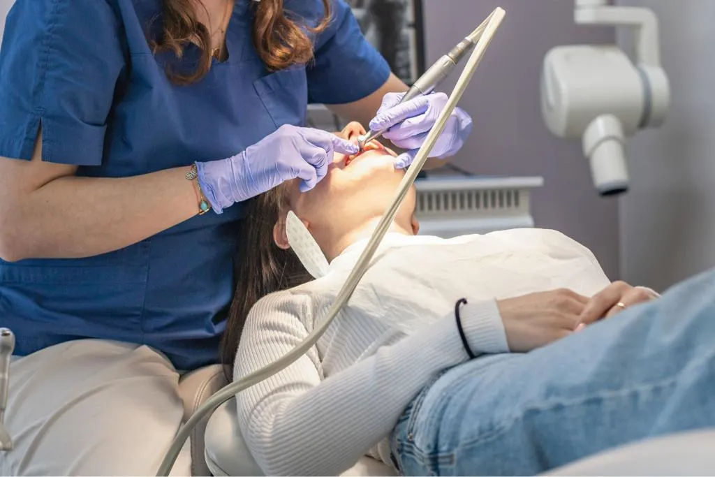 Dental hygienist using specialized instruments to perform a dental procedure on a patient in a bright clinic promoting preventive oral care and gum health