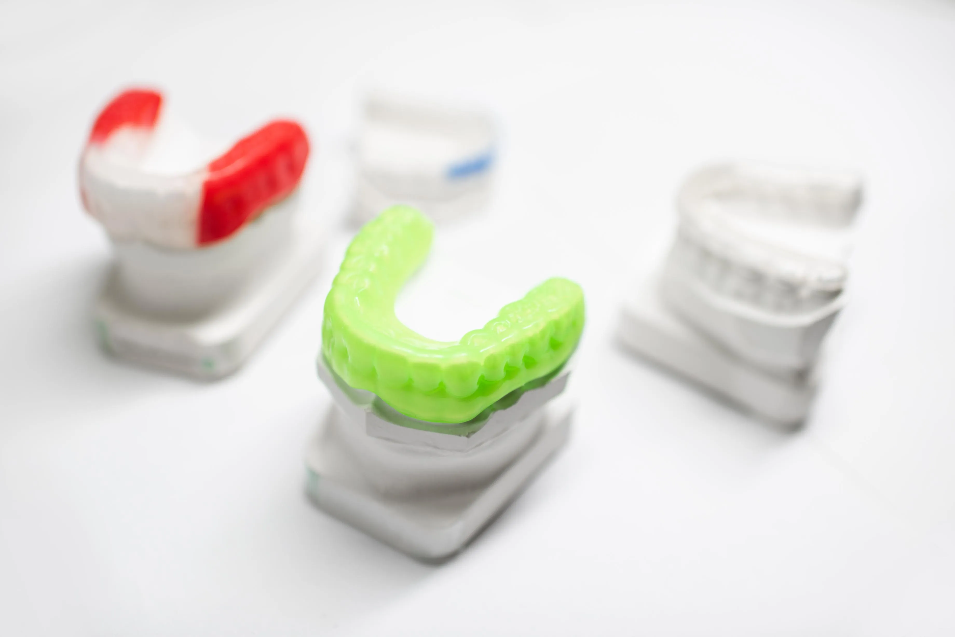 Collection of colorful custom dental mouthguards displayed on a white background showcasing options for sports players and patients needing teeth protection during physical activity