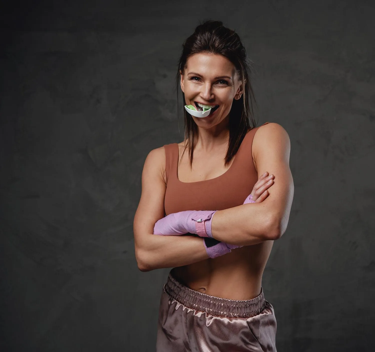 Confident female athlete wearing a sports outfit and holding a mouthguard smiling after training symbolizing the benefits of dental protection and athletic confidence