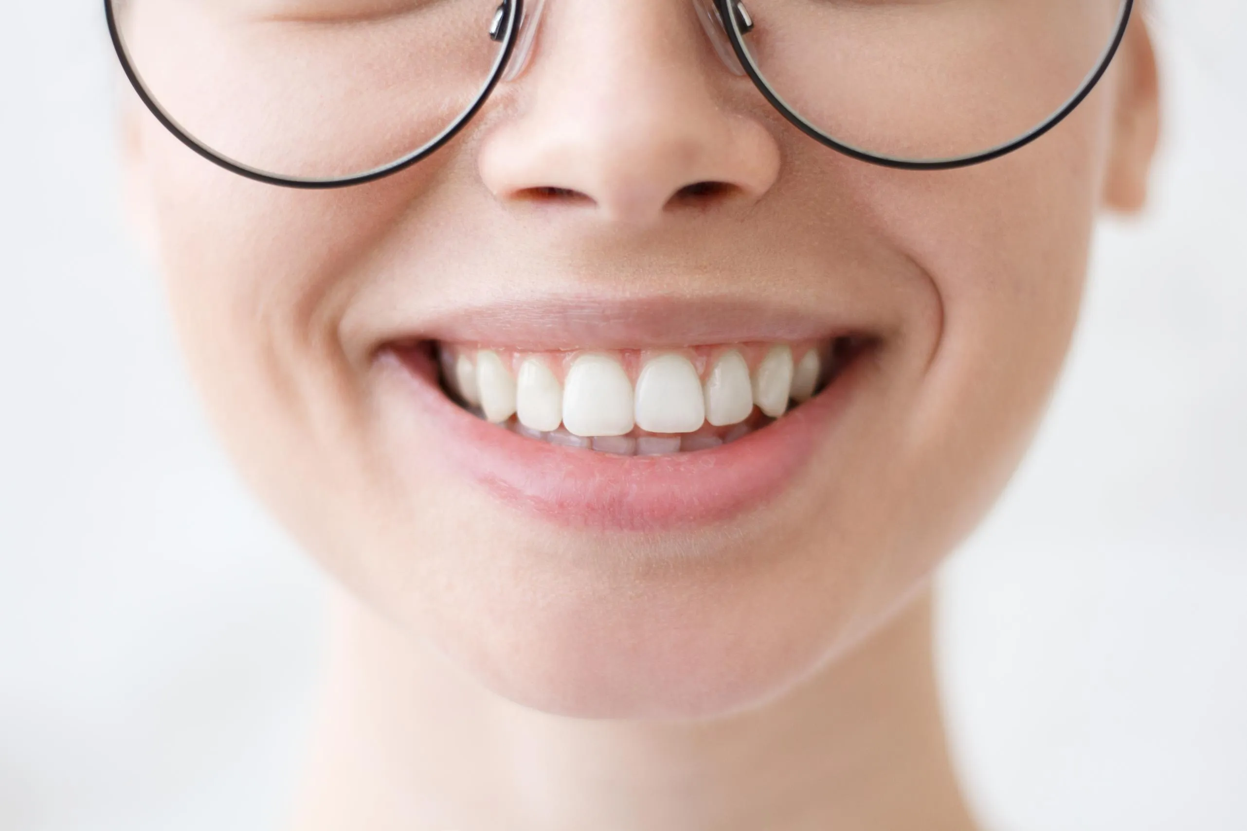 Smiling woman wearing glasses showing healthy white teeth after dental cleaning representing confidence and excellent oral hygiene