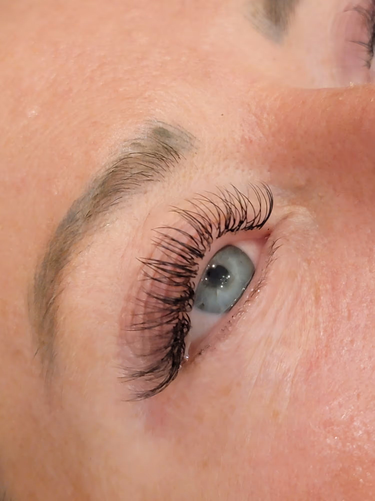 Close-up of an eye with long, curled eyelashes and a blue iris looking upward.
