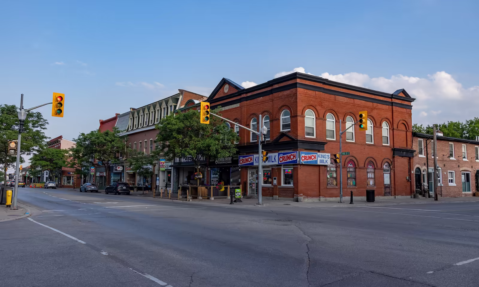 Street corner with brick buildings, traffic lights, and shops under a clear blue sky.
