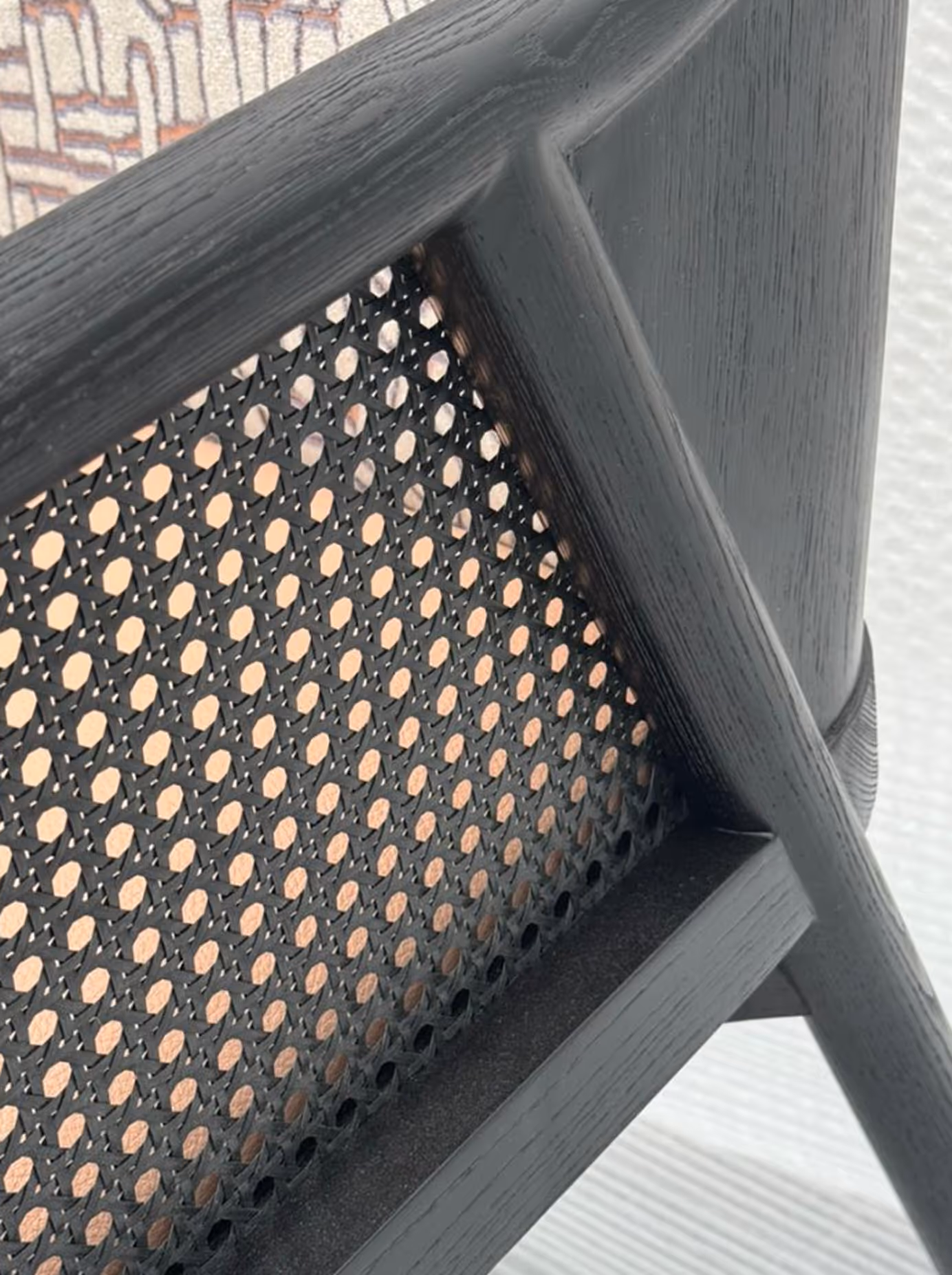 Close-up of a black wooden chair with a woven cane backrest.