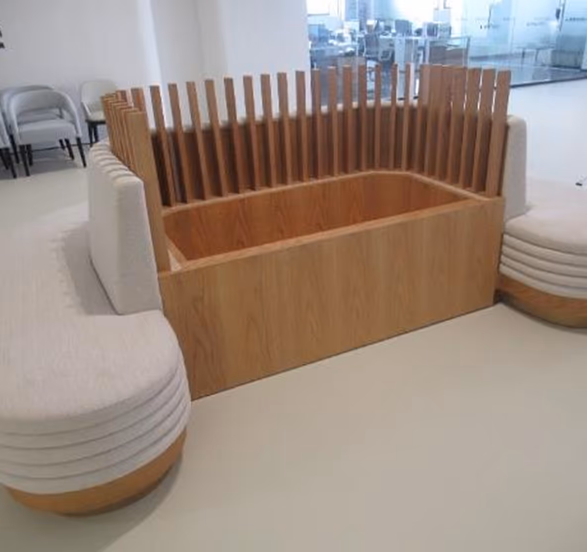 Corner seating area with white cushioned benches and a wooden planter box with vertical slats in the center.