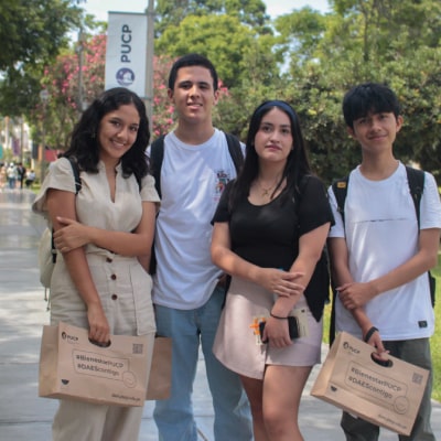 Cuatro estudiantes posan al aire libre en el campus universitario durante una jornada de actividades
