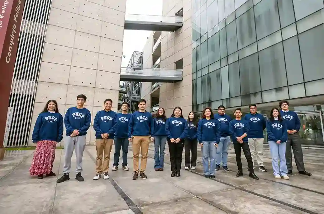 Delegación de estudiantes PUCP con buzos institucionales posa en el campus universitario antes de participar en el CADE Universitario 2025