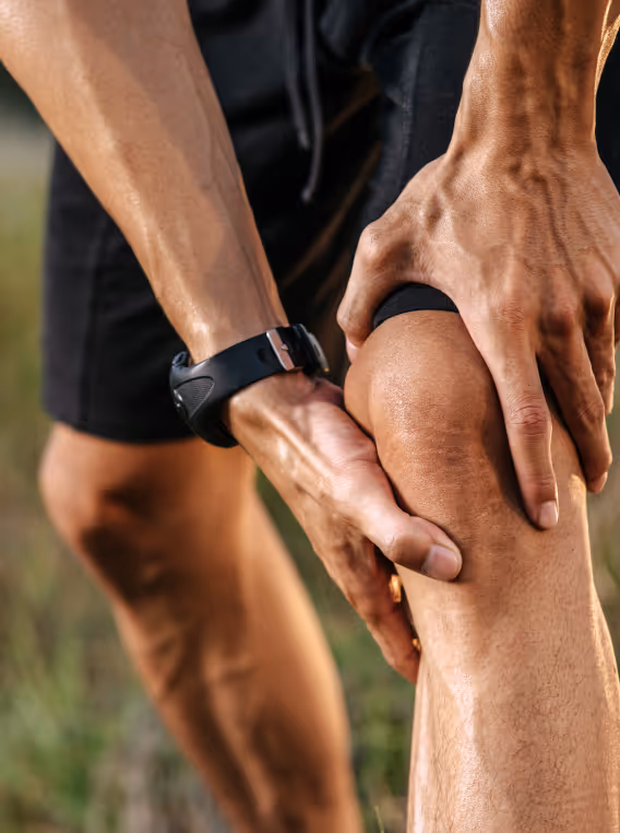 A man grips his injured knee, highlighting the application of EPAT Shockwave Therapy for treatment and recovery. 
