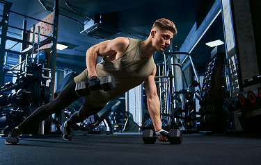 Focused man lifting dumbbells in a gym, representing enhanced strength, recovery, and immunity supported by Vitamin C injections.