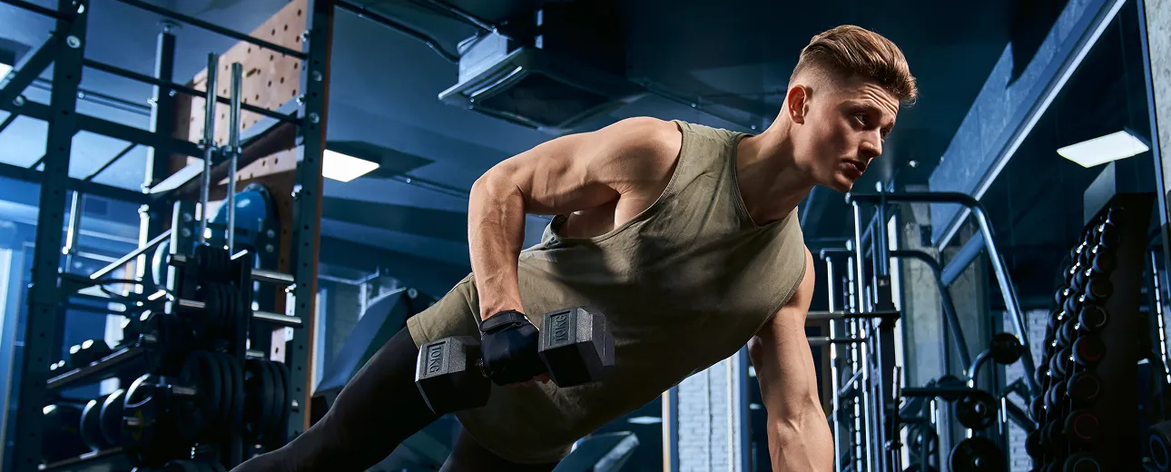 Focused man lifting dumbbells in a gym, representing enhanced strength, recovery, and immunity supported by Vitamin C injections.