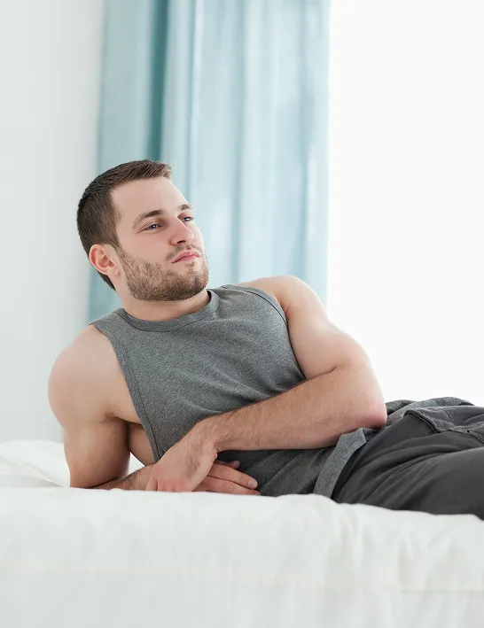 Relaxed man resting on bed in athletic wear, symbolizing recovery and detoxification benefits from Glutathione injections.