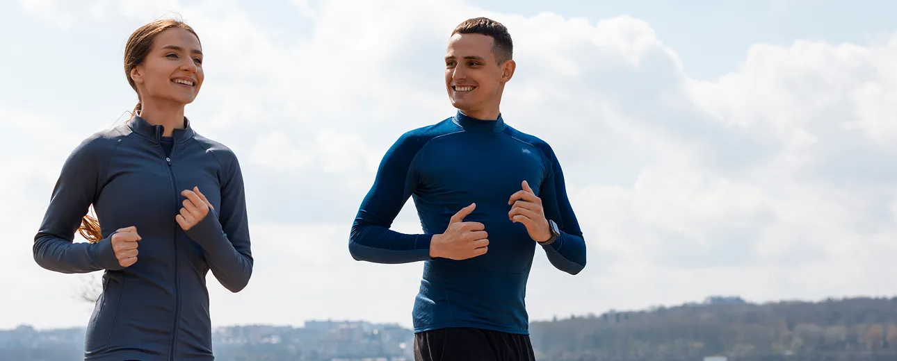Smiling man and woman jogging outdoors, representing improved energy, immune support, and vitality from Glutathione injections.