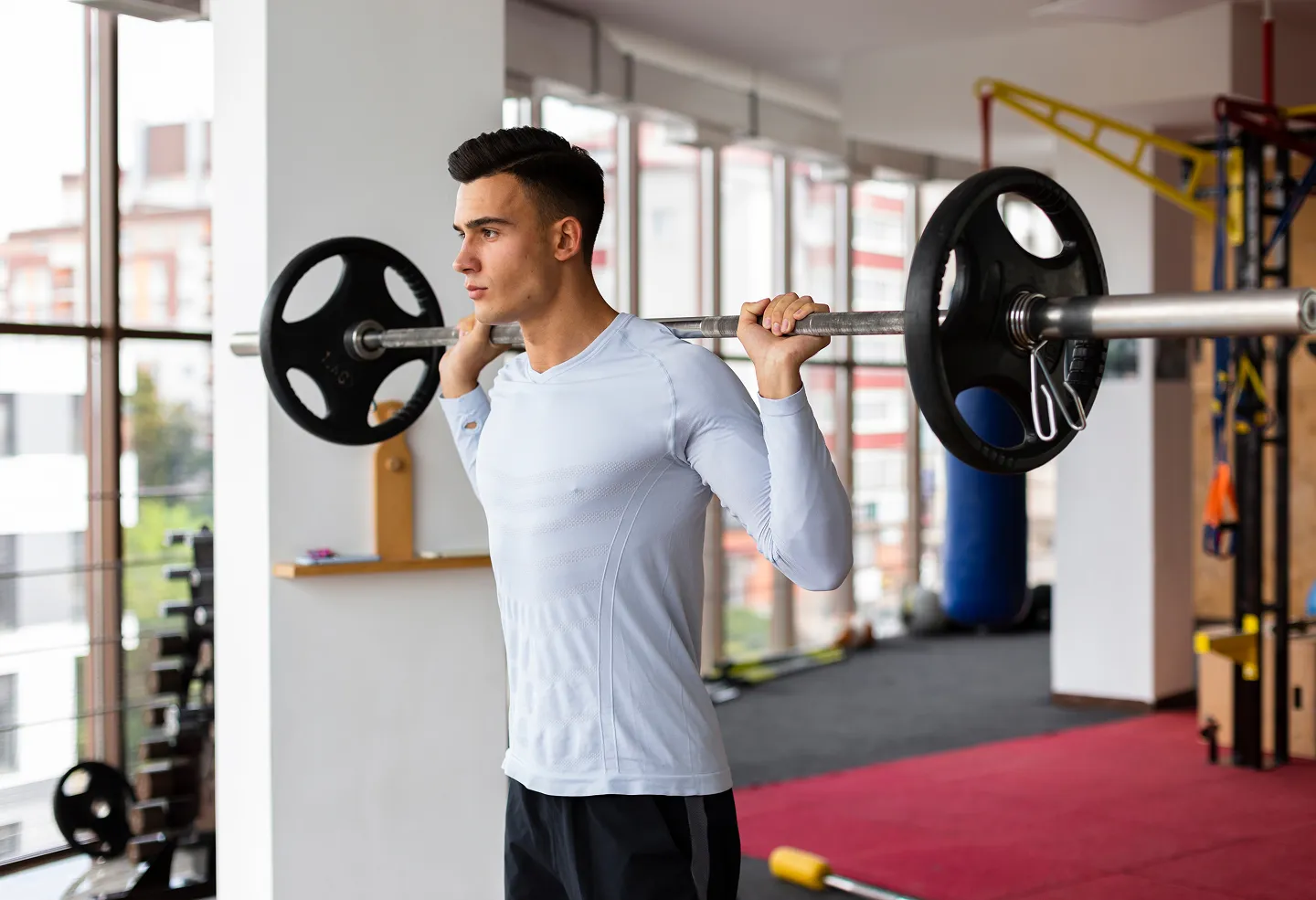 Young man lifting a barbell at the gym, representing enhanced physical performance and cellular recovery with Glutathione injections.