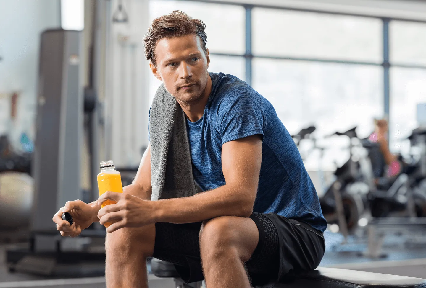 Man resting at the gym with a towel and energy drink, representing post-workout recovery and metabolism support from MIC lipotropic injections