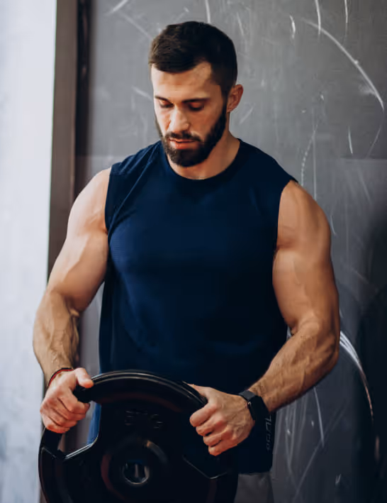 Muscular man lifting weights, highlighting enhanced workout recovery and energy from Vitamin B Complex injections.