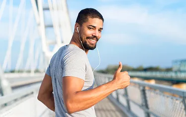 Smiling man in a gray t-shirt giving a thumbs up while exercising outdoors, representing boosted energy and weight loss benefits from MIC lipotropic injections at Gameday Men’s Health.