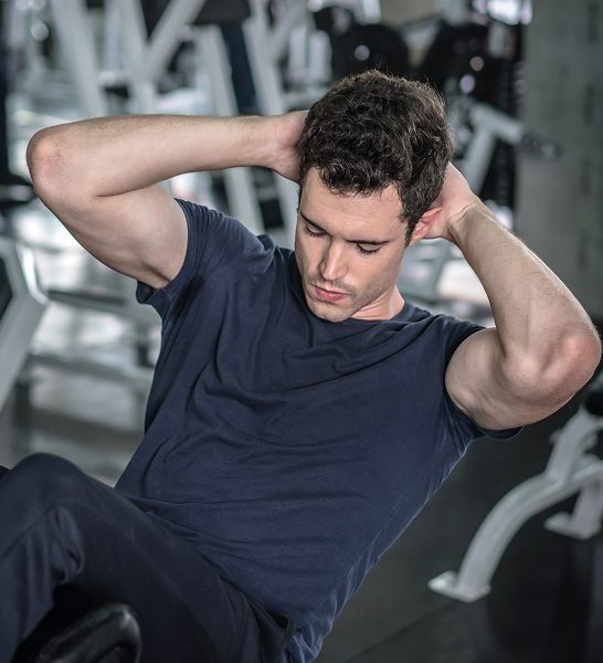 Man performing abdominal crunches at the gym, highlighting fitness and muscle recovery benefits associated with Tri-Amino Acid injections for men.