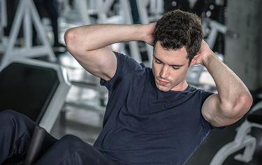 Man performing abdominal crunches at the gym, highlighting fitness and muscle recovery benefits associated with Tri-Amino Acid injections for men.