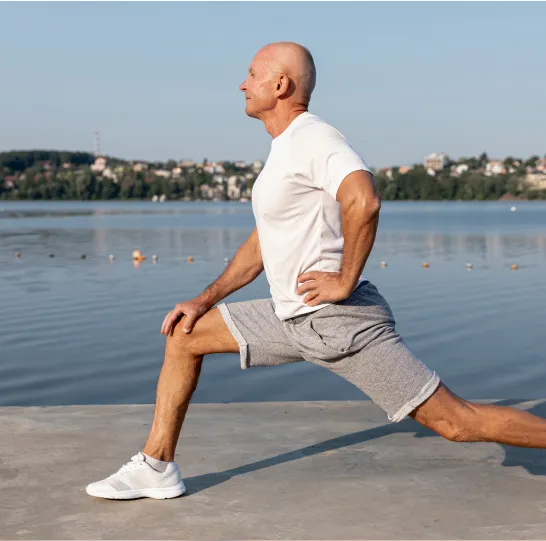 Older man stretching outdoors by a lake, benefiting from improved mobility and vitality with GHRH peptide therapy