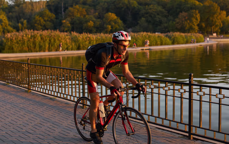 Man cycling by the lake, feeling energized and revitalized through Vitamin B12 injections for enhanced stamina