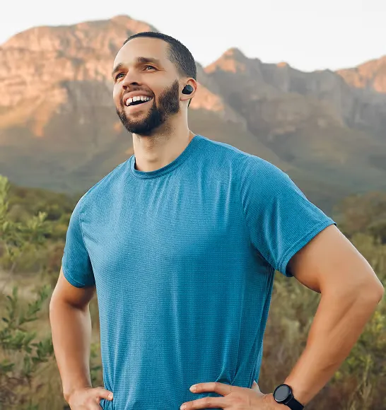Fit man smiling post-workout in a scenic outdoor setting, representing the energy, immune support, and antioxidant benefits of Vitamin C injections for men.