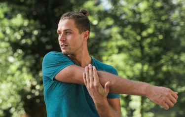 Young man stretching outdoors in athletic wear, highlighting the muscle recovery and immune-boosting benefits of Vitamin C injections for men.