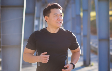 Smiling man jogging outdoors in the sun, reflecting the energy, immune support, and detoxification benefits of glutathione injections.