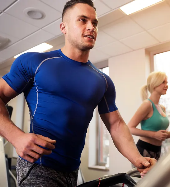 Fit man running on a treadmill at the gym, representing improved stamina and sexual health benefits from GAINSWave® therapy.