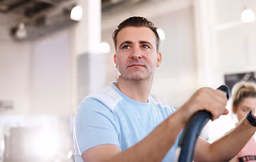 Man working out on cardio machine at gym, representing boosted stamina and vitality from Sermorelin therapy