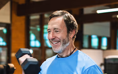 Middle-aged man lifting weights indoors, showcasing strength and energy benefits of Sermorelin peptide therapy