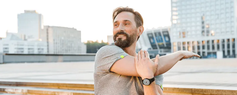 Middle-aged man stretching outdoors in the city, symbolizing strength, mobility, and the benefits of testosterone therapy.