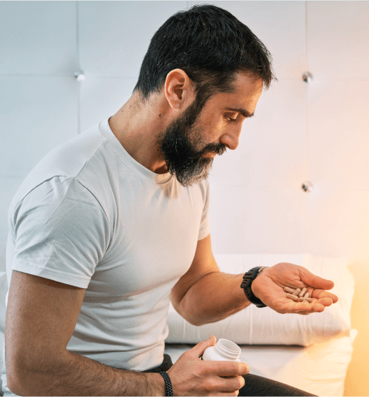Man examining oral testosterone pills, highlighting convenient at-home treatment option.