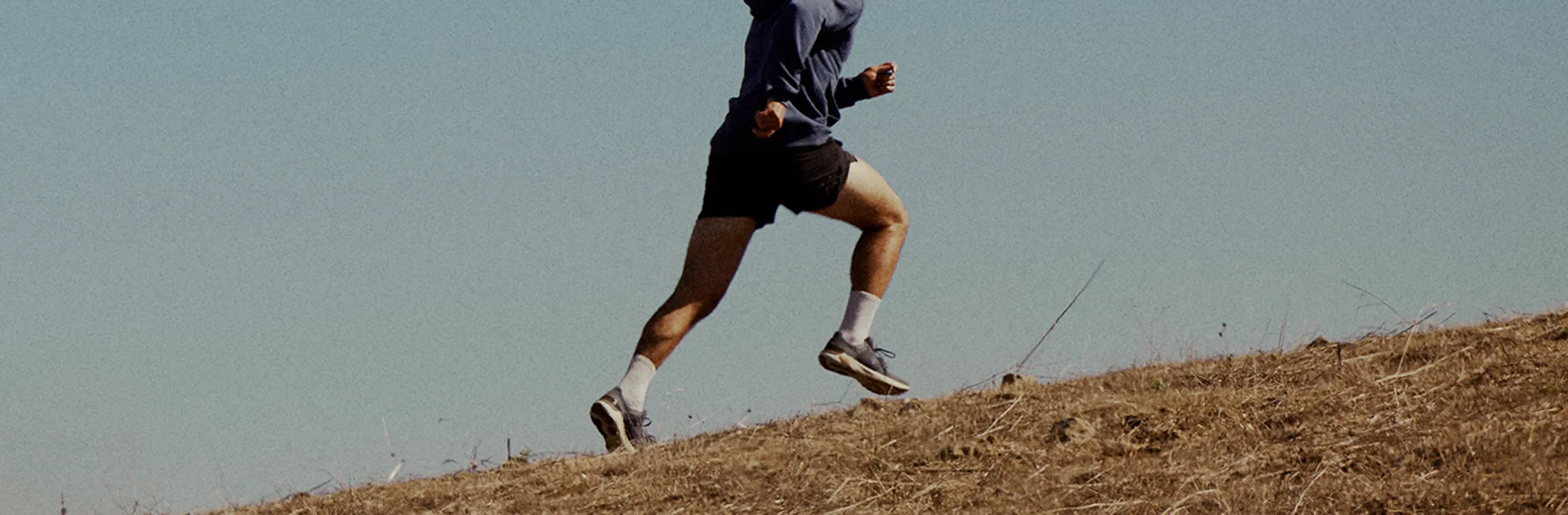 Runner training hard on a hillside during early morning light, embodying the physical transformation and confidence men gain through Gameday treatments.