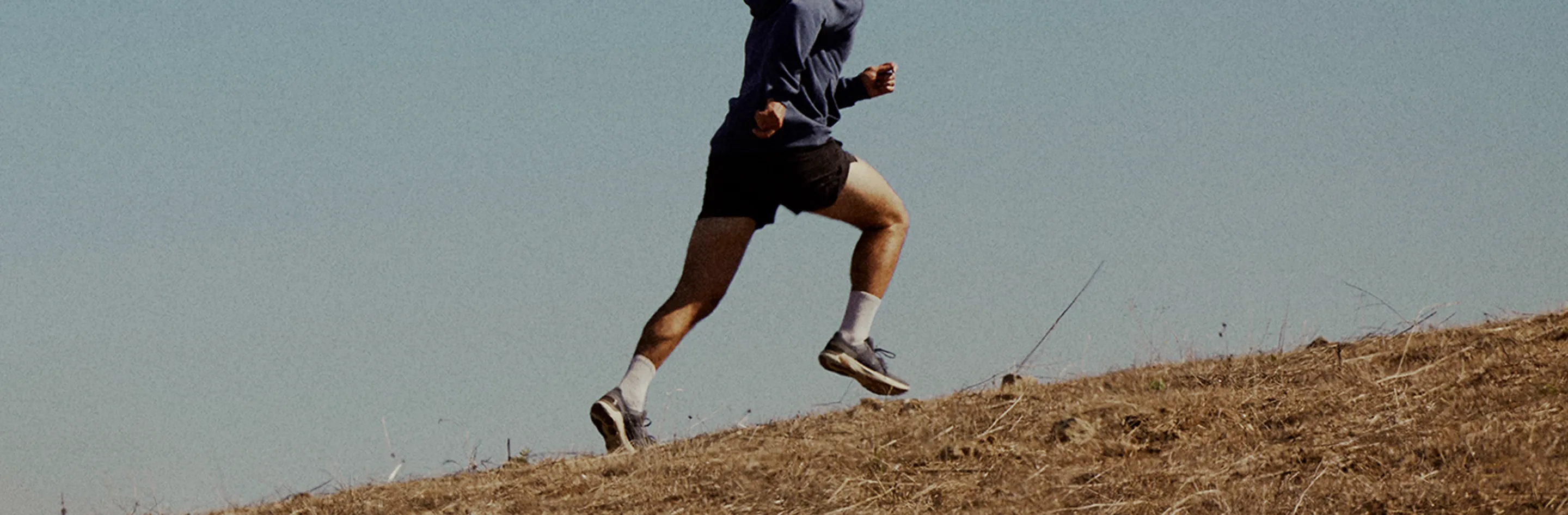 Runner training hard on a hillside during early morning light, embodying the physical transformation and confidence men gain through Gameday treatments.