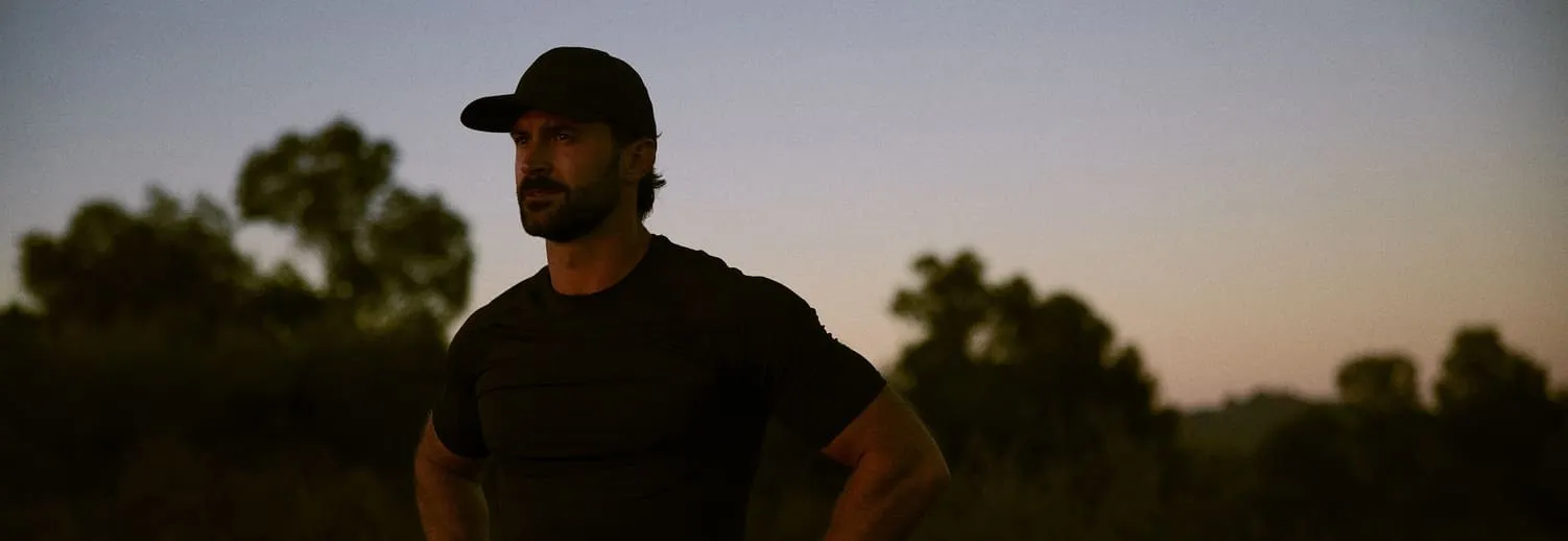 Man standing at sunset and looking thoughtful, representing reflection and the journey toward improved men’s health and vitality.