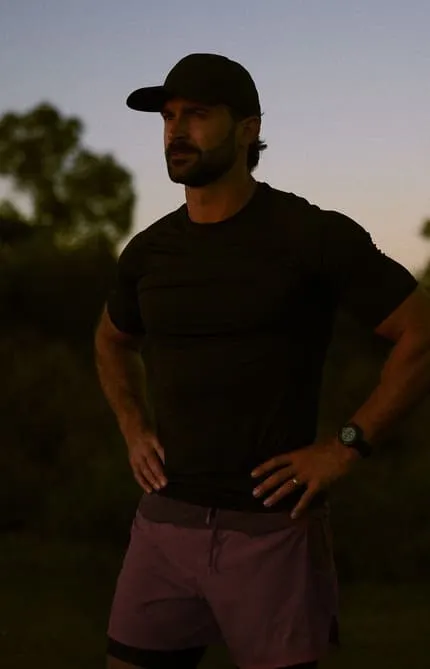 Man standing at sunset and looking thoughtful, representing reflection and the journey toward improved men’s health and vitality.