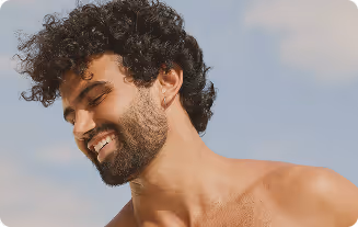 Smiling man showing confidence, representing improved hair density and appearance after hair loss treatments.