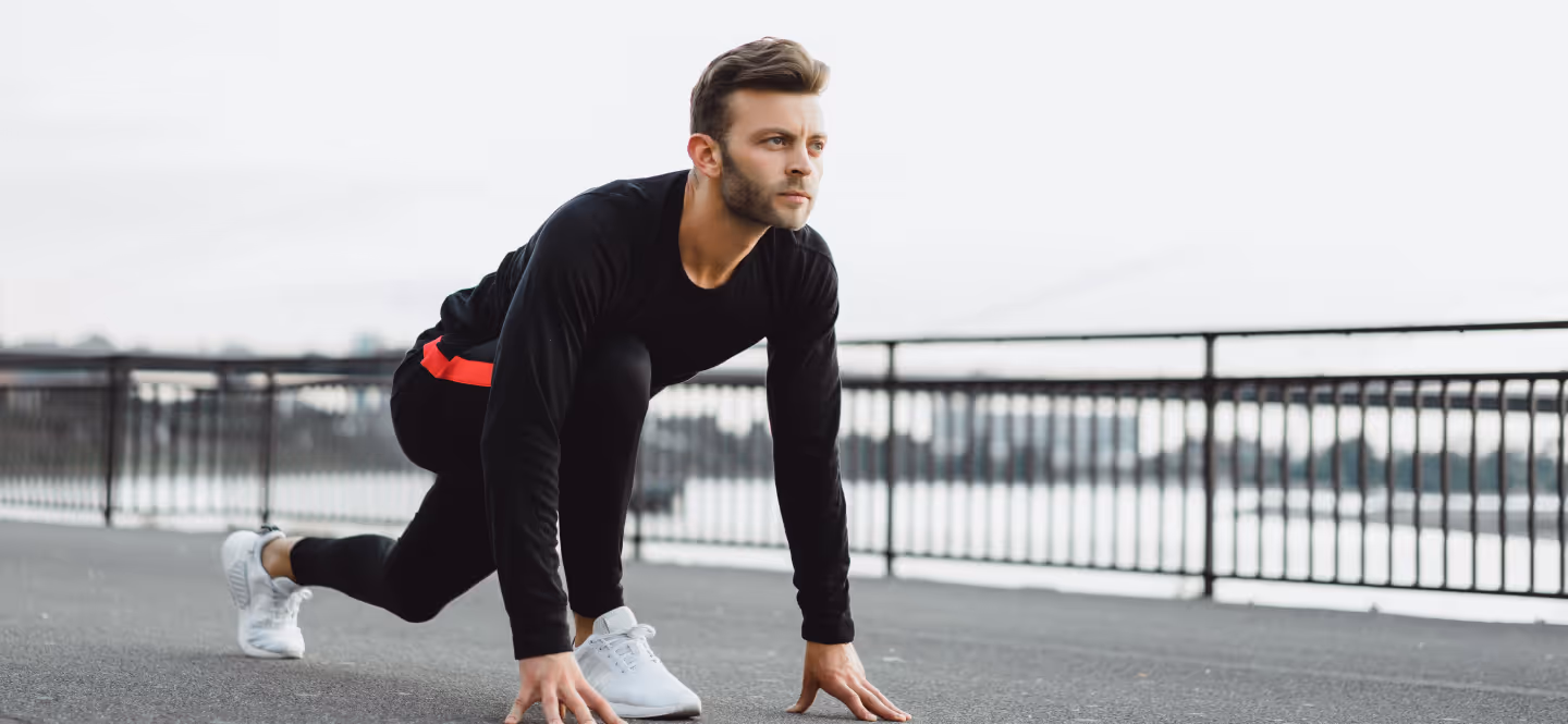 Focused man preparing for a run on a city bridge, representing motivation, transformation, and the start of a wellness journey with Gameday Men’s Health.