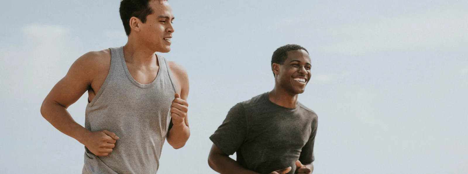 Two men jogging outdoors and smiling, representing increased energy and active lifestyle.