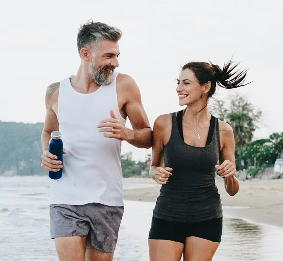 Middle-aged couple running on the beach.