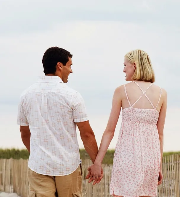 Young couple holding hands walking outside.