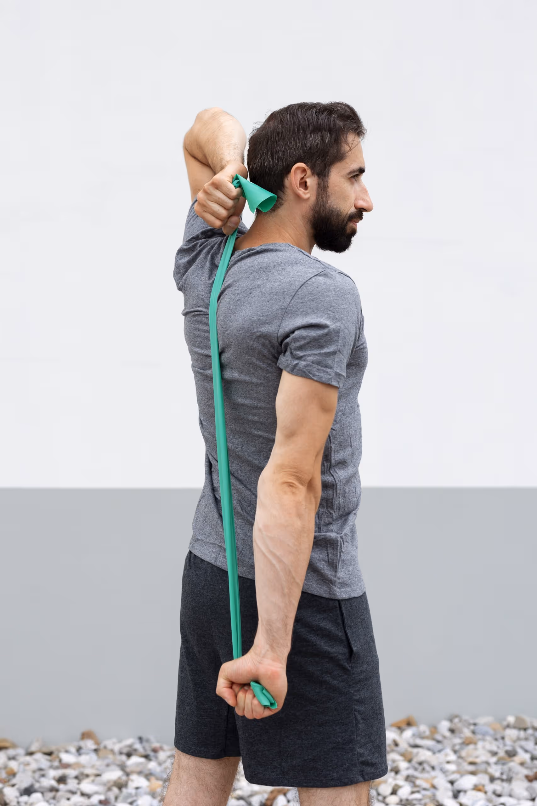 A man wearing a green band around his neck, standing against a neutral background. 