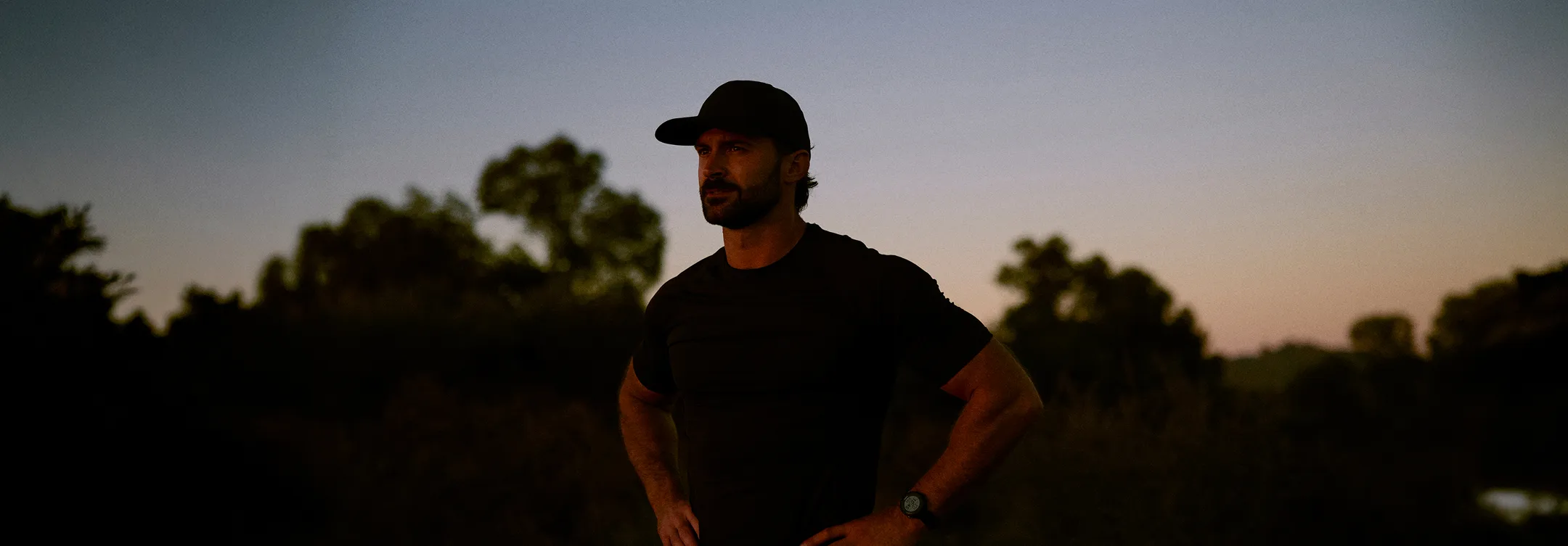 Man standing at sunset and looking thoughtful, representing reflection and the journey toward improved men’s health and vitality.